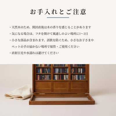 お手入れとご注意のカード。柔らかい布を添えた、開いた状態のミニチュア本棚の静物写真。
