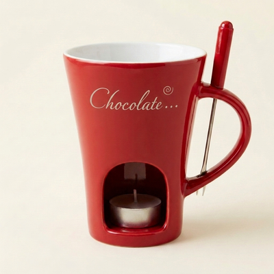 クラシックレッドのマグ、前面に銀色の「Chocolate…」プリント、右側の取っ手、底のキャンドル窓と赤い持ち手のフォーク付き