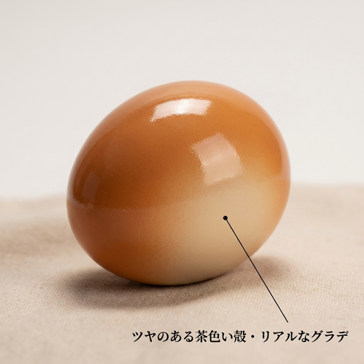 ツヤのある茶色からクリーム色へのグラデーションを示す卵型トイのスタジオ写真