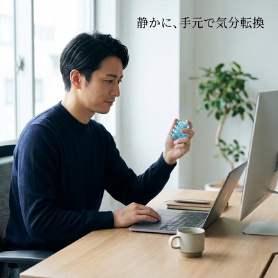 デスクで静かにクリアブルーのフィジェットを触る日本人の会社員