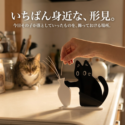 台所で女性の手がひげを一本、一輪挿しに挿している。後ろに猫がいる。