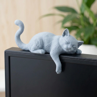 モニターのフチに垂れる短毛グレーのねこ